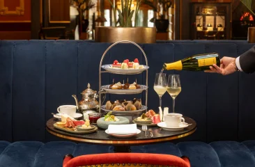 Een elegante tafel met high tea, inclusief thee, gebak en champagne.